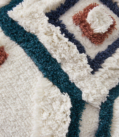 Close-up shag pillow texture with teal and navy borders and rust stitched diamond center