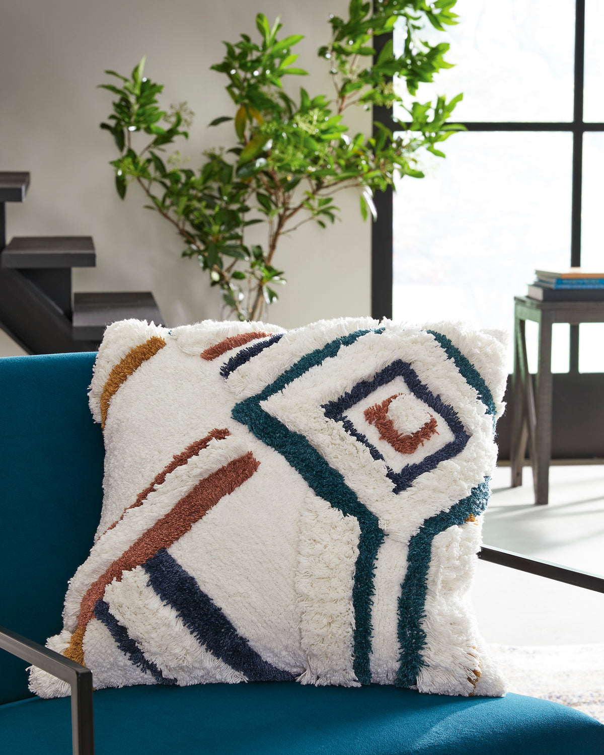 Square throw pillow with cream shag fabric and navy, teal, and rust geometric design