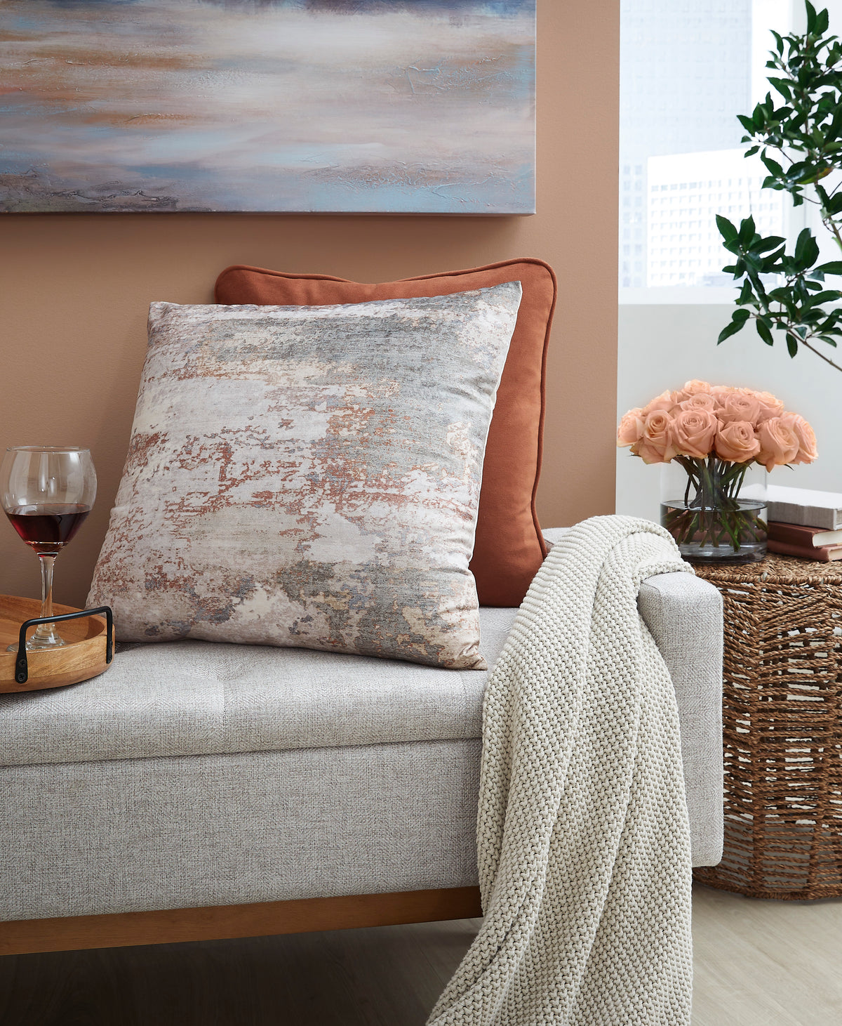 Square decorative pillow with distressed abstract print in beige, gray, and rust tones