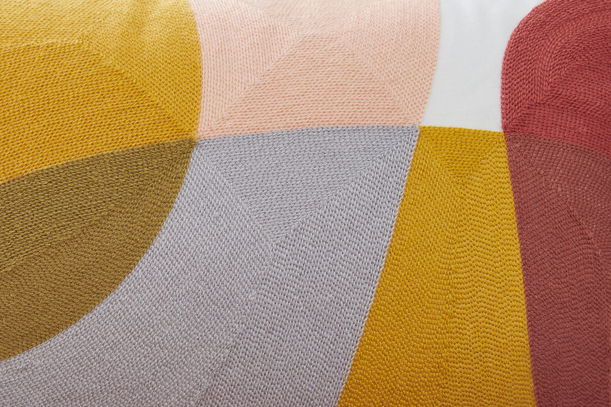 Close-up of geometric pillow fabric texture in mustard, gray, blush, and rust