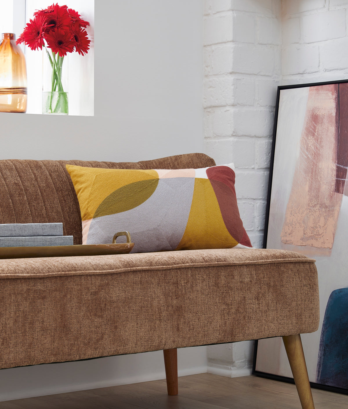 Geometric accent pillow with mustard, gray, and blush tones on a sofa