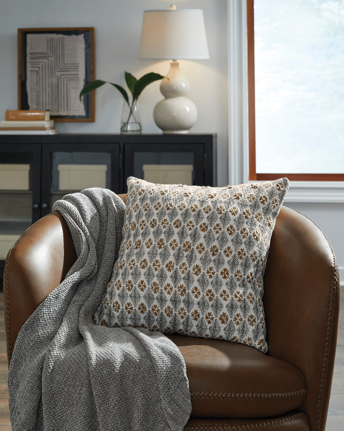 Decorative throw pillow with light gray base and small brown floral pattern