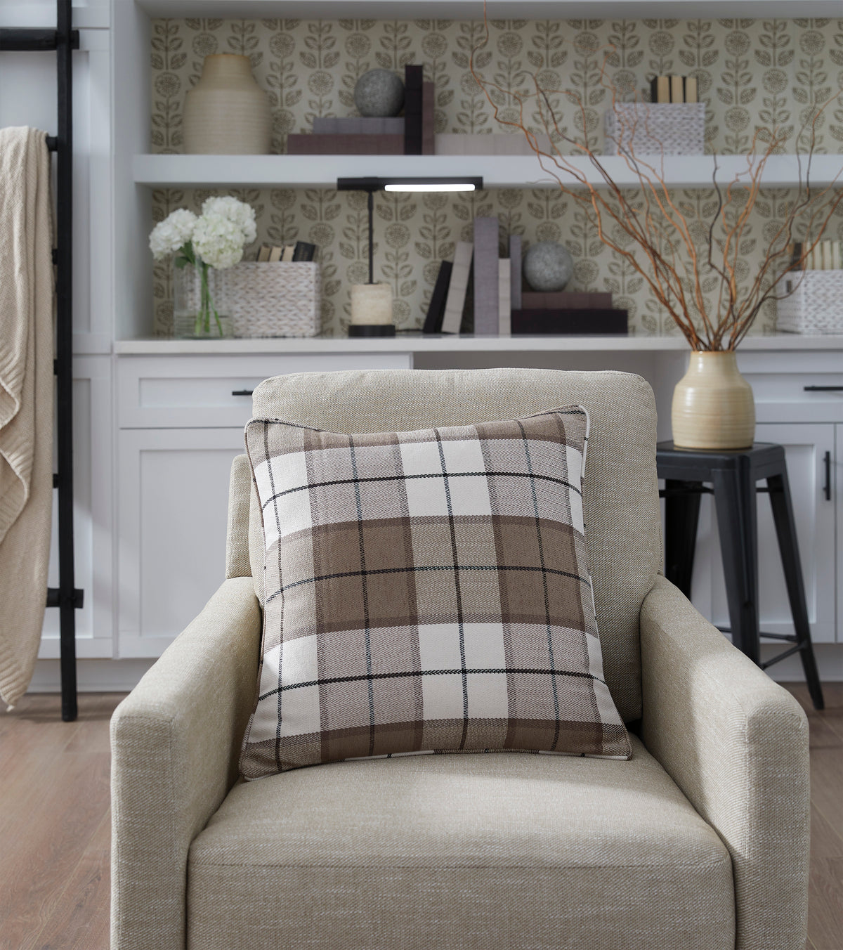 Plaid throw pillow on beige armchair with square edges and dark trim