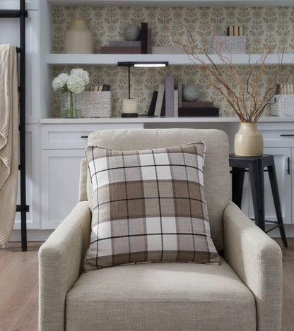 Plaid throw pillow on beige armchair with square edges and dark trim