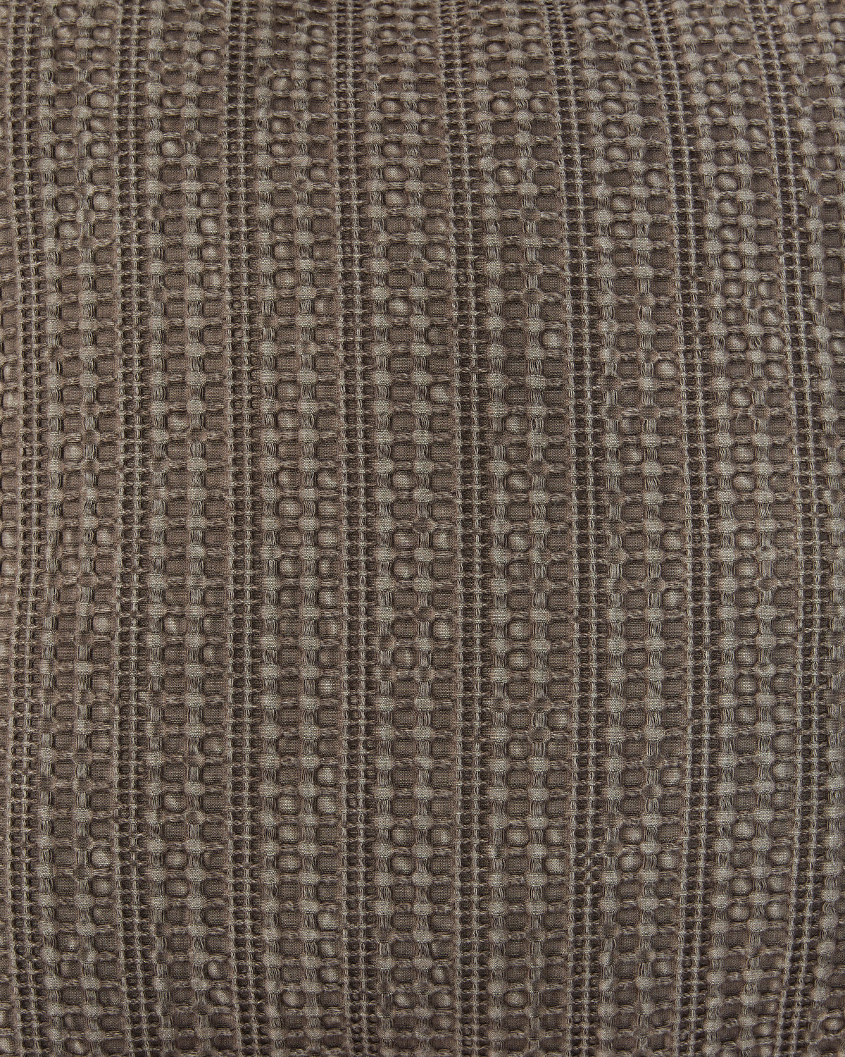 Close-up of taupe-brown textured woven fabric with repeating stitched pattern
