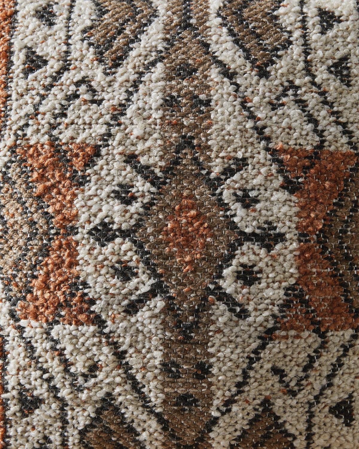 Close-up of woven geometric fabric texture in cream, brown, and rust tones