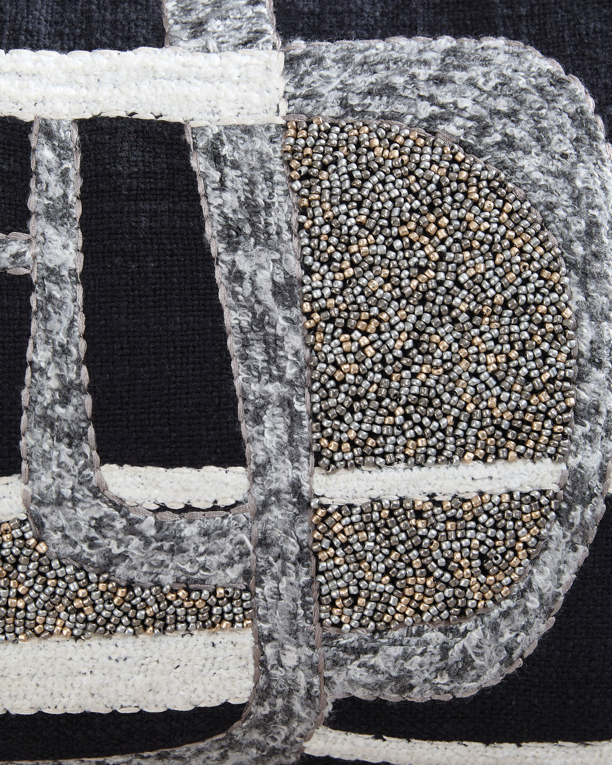 Close-up of embroidered black and gray pillow fabric with beaded gold and white details