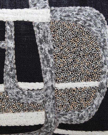 Close-up of embroidered black and gray pillow fabric with beaded gold and white details
