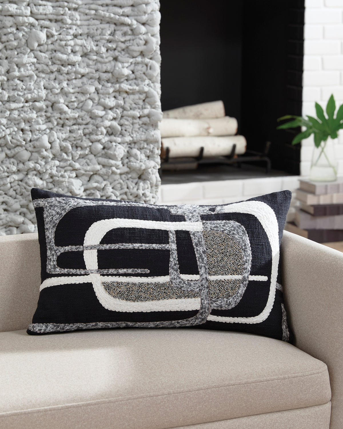 Black and gray rectangular pillow with white geometric emblem stitched on front
