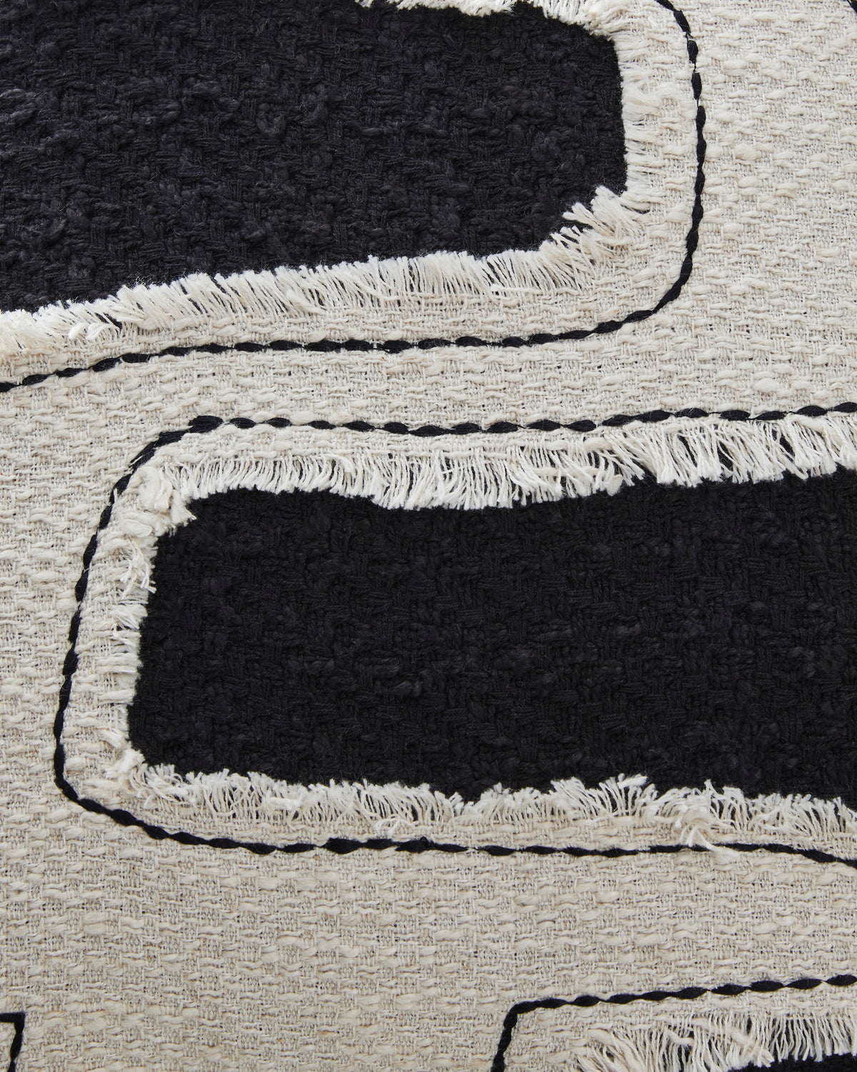 Black-and-cream throw pillow embroidery close-up with looped stitched lines