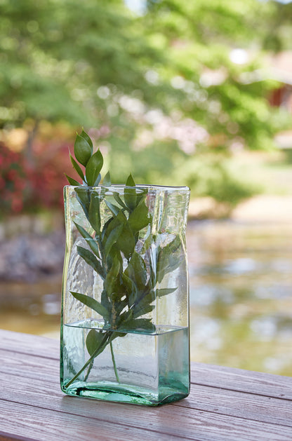 Green-tinted glass vase cube with clear sides, holding leafy stems