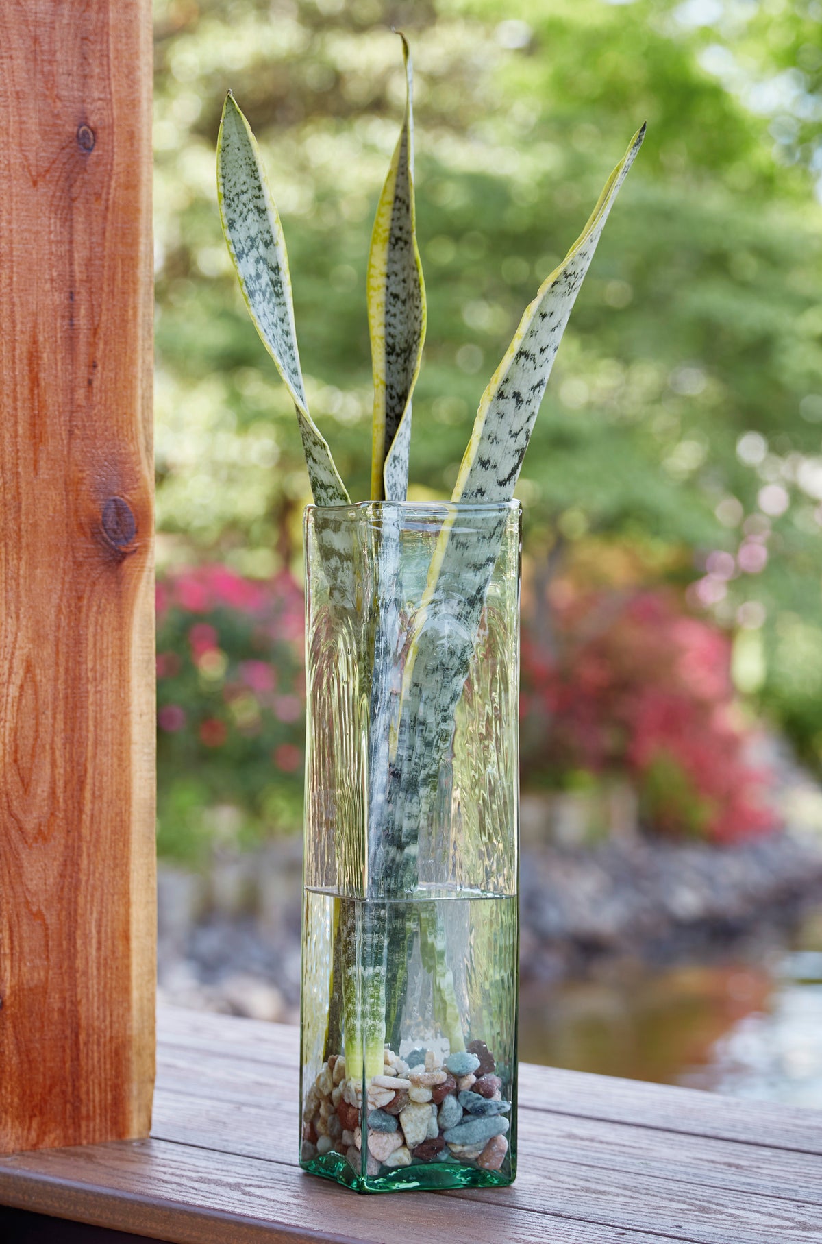Tall green glass vase with tied stems and decorative filler stones