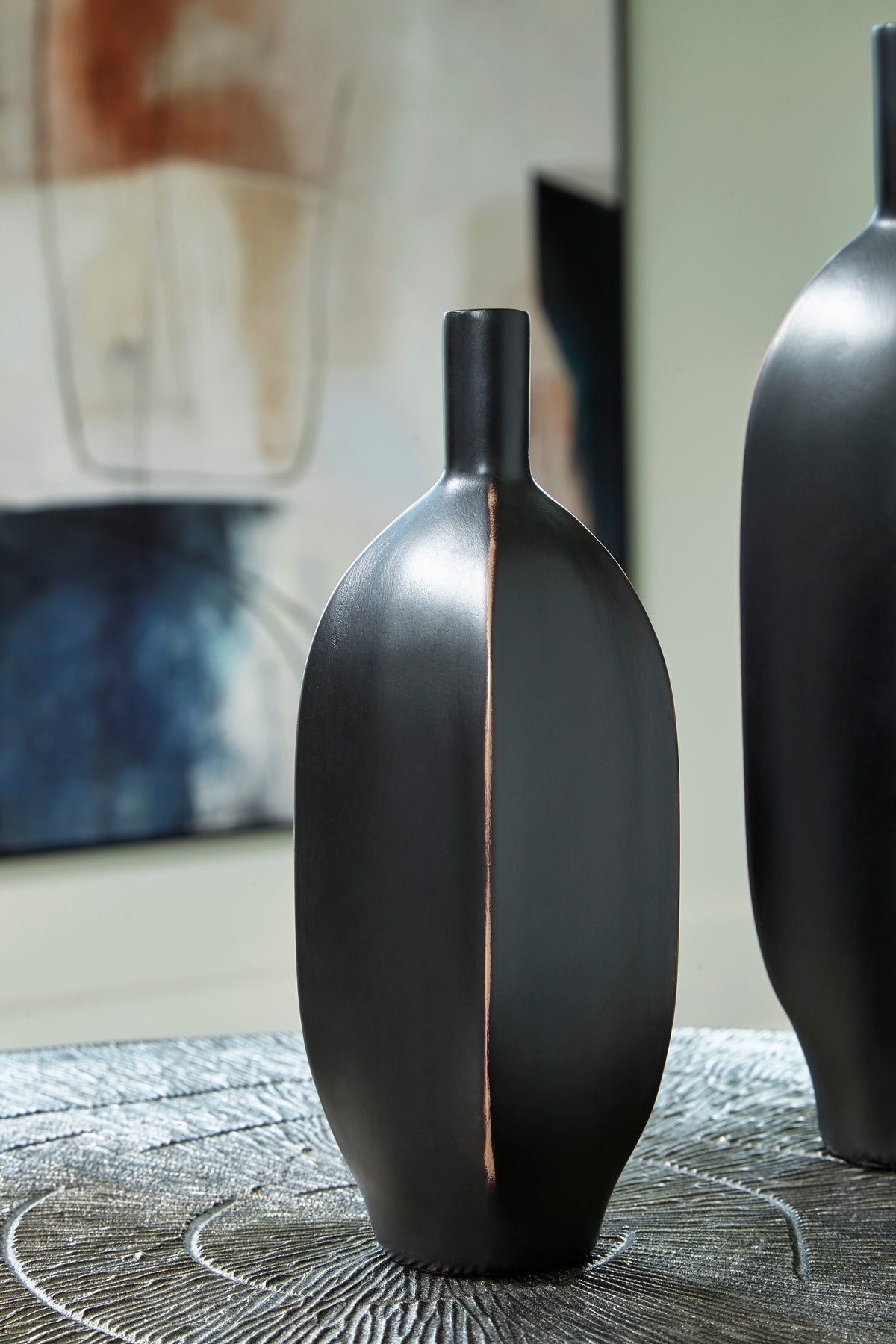 Black ceramic vase with tall neck and copper-toned vertical accent seam.