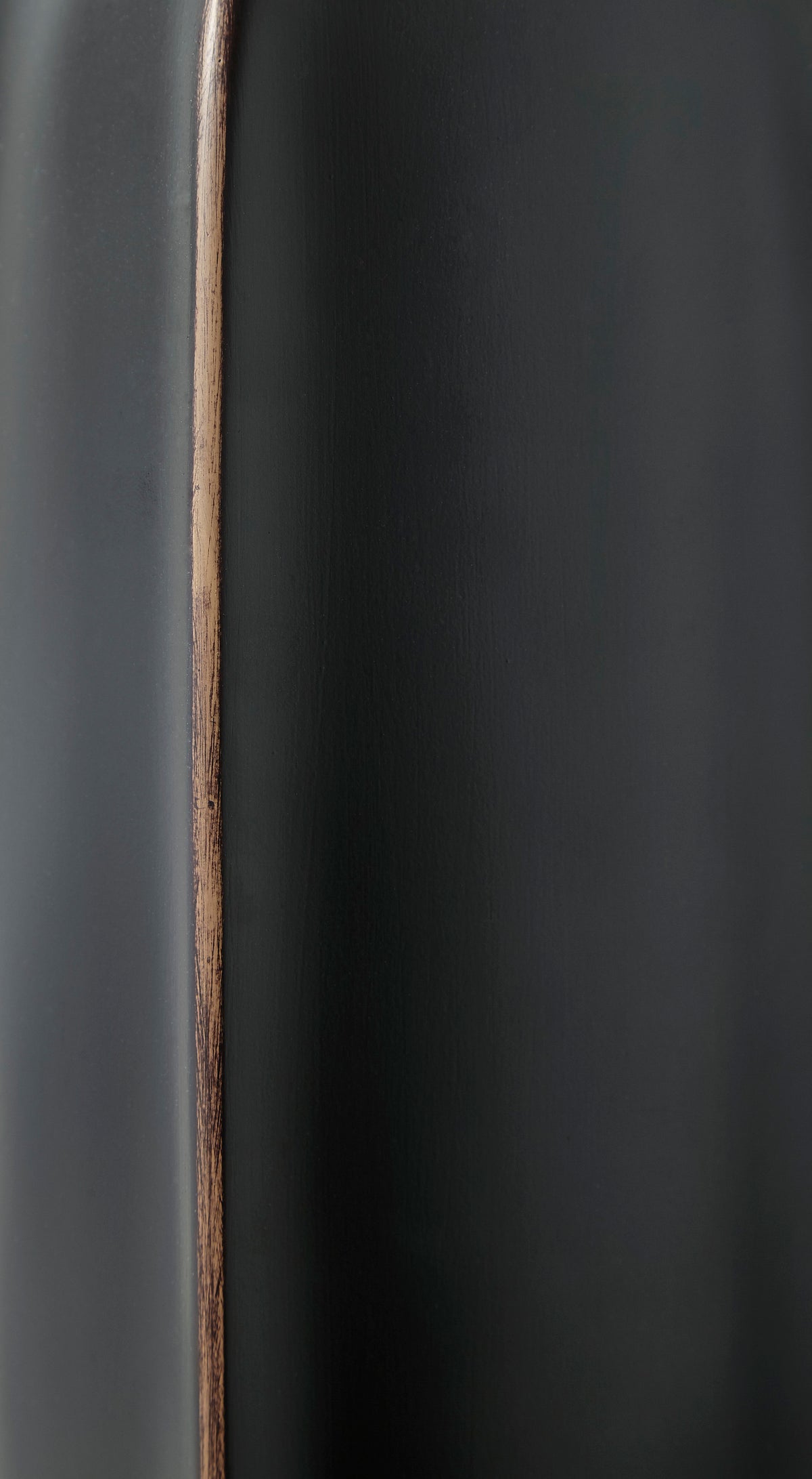 Matte black vase close-up with vertical copper seam line