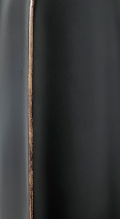 Matte black vase close-up with vertical copper seam line