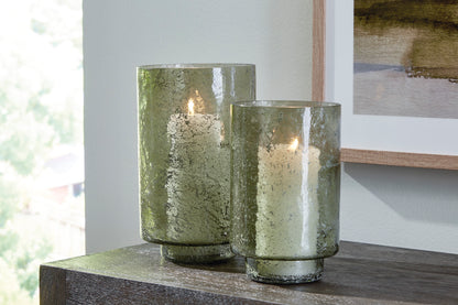 Set of 2 green speckled glass candle holders with open tops, candles lit inside.