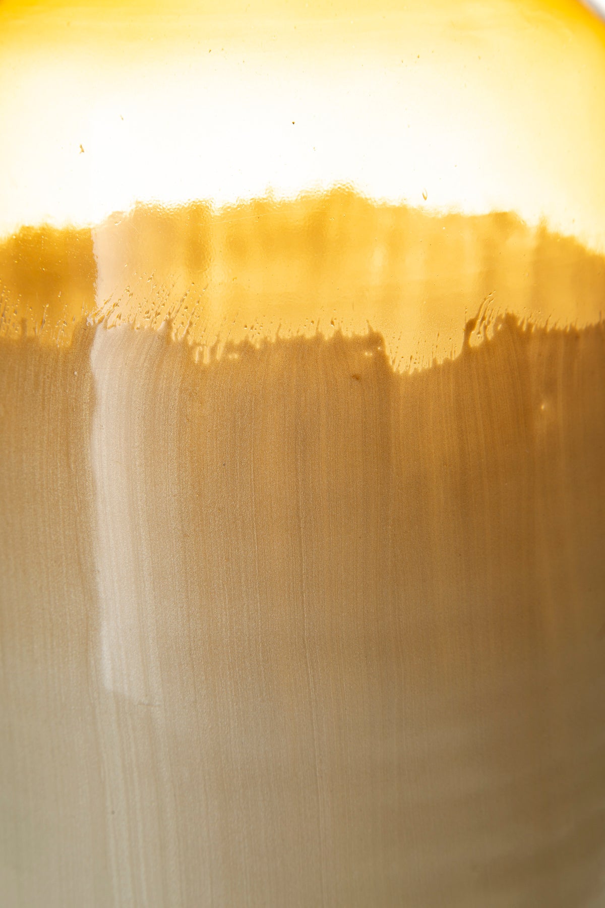 Close-up of amber glaze band and cream-to-gray body texture on ceramic vase.