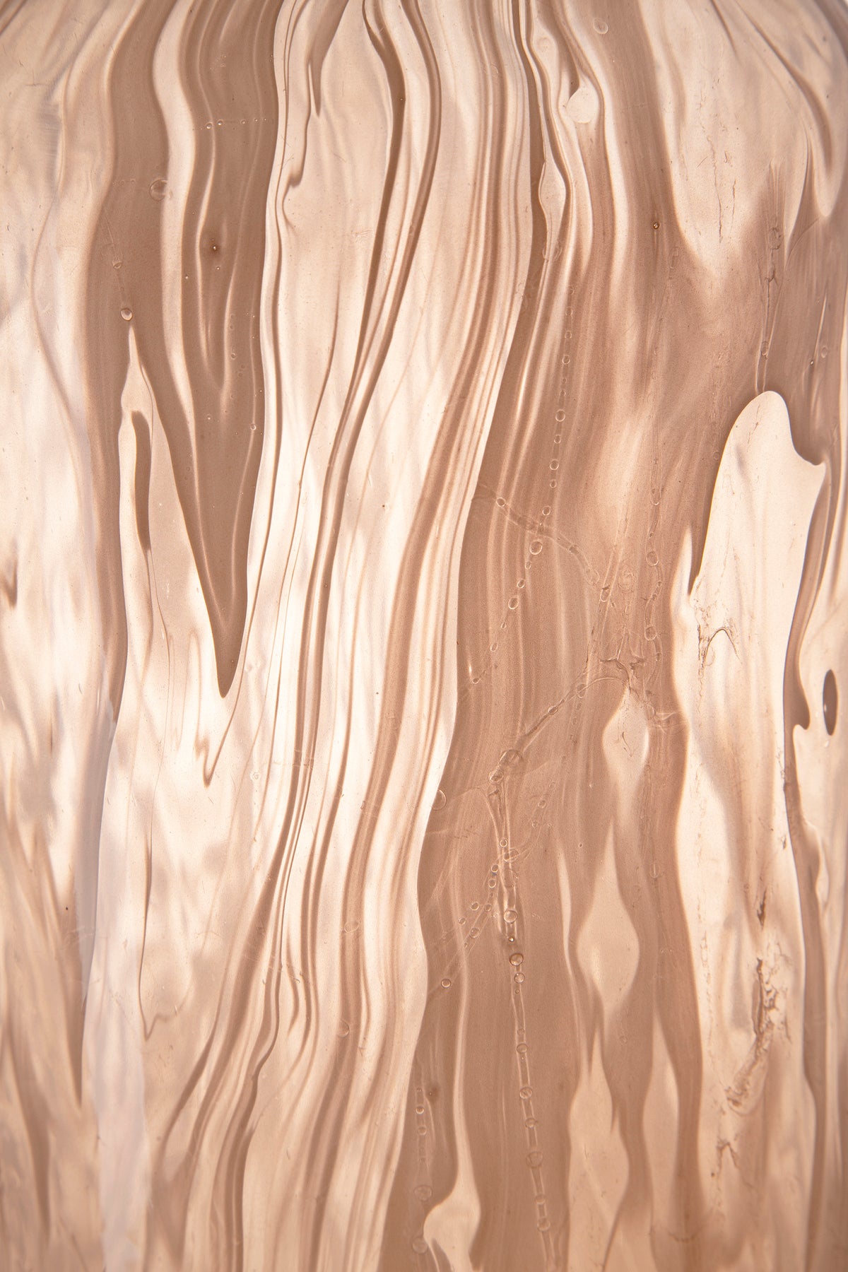 Peach glass vase with glossy marbled waves across the surface