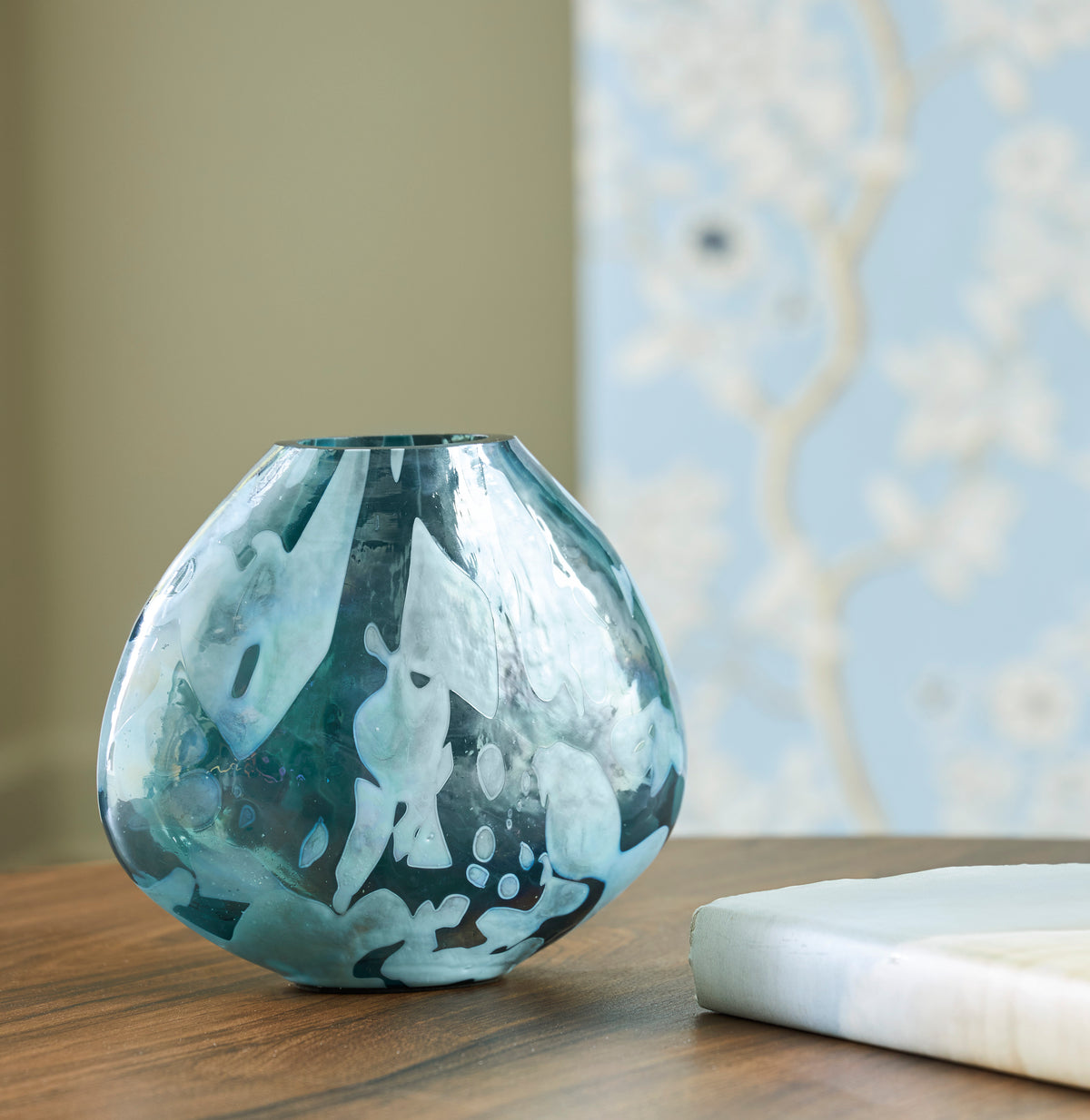Teal marbled glass vase on table with fluted top rim