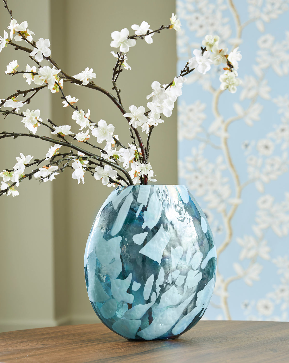 Teal marbled glass vase standing with white flower branches and fluted opening