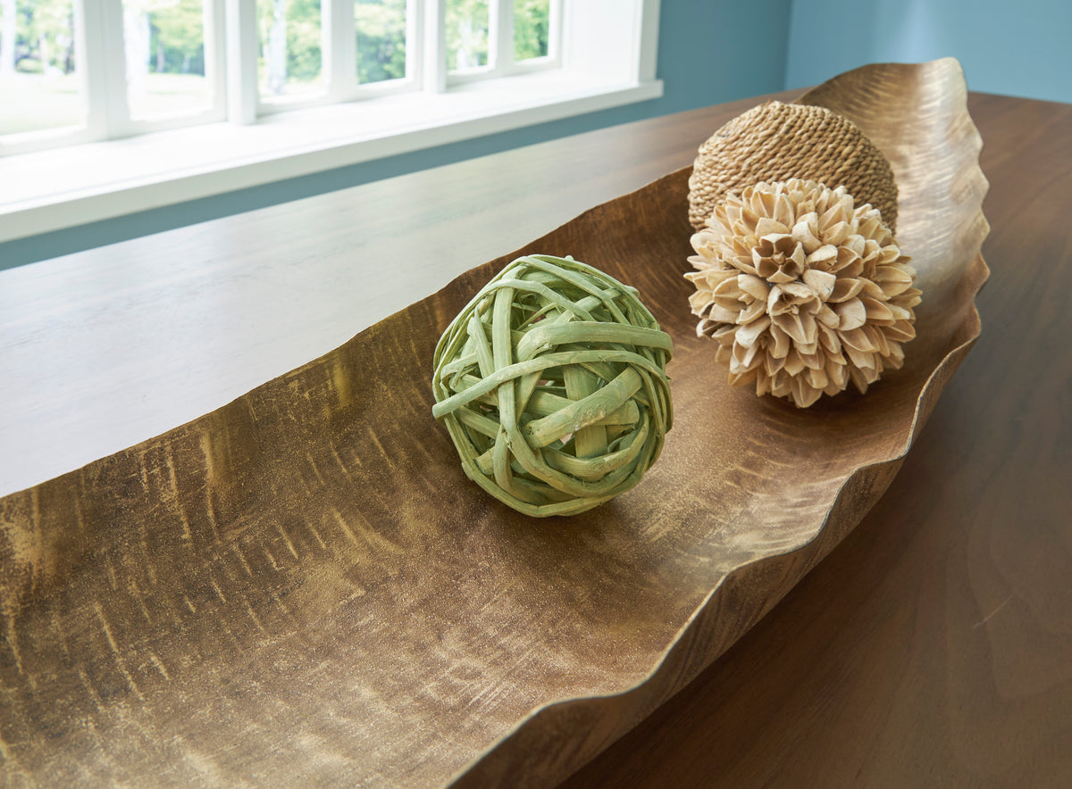 Golden-brown curved wood serving tray with green and tan pom-pom decor
