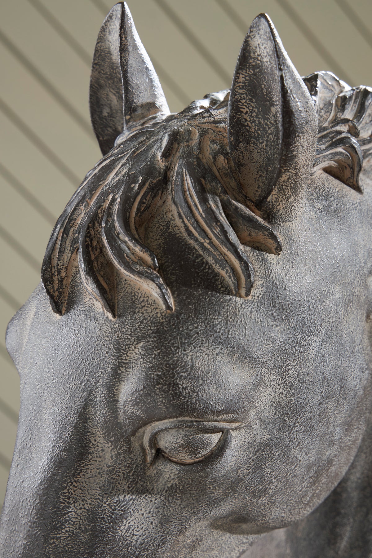 Close-up of grey horse head sculpture with detailed mane and raised ears on base