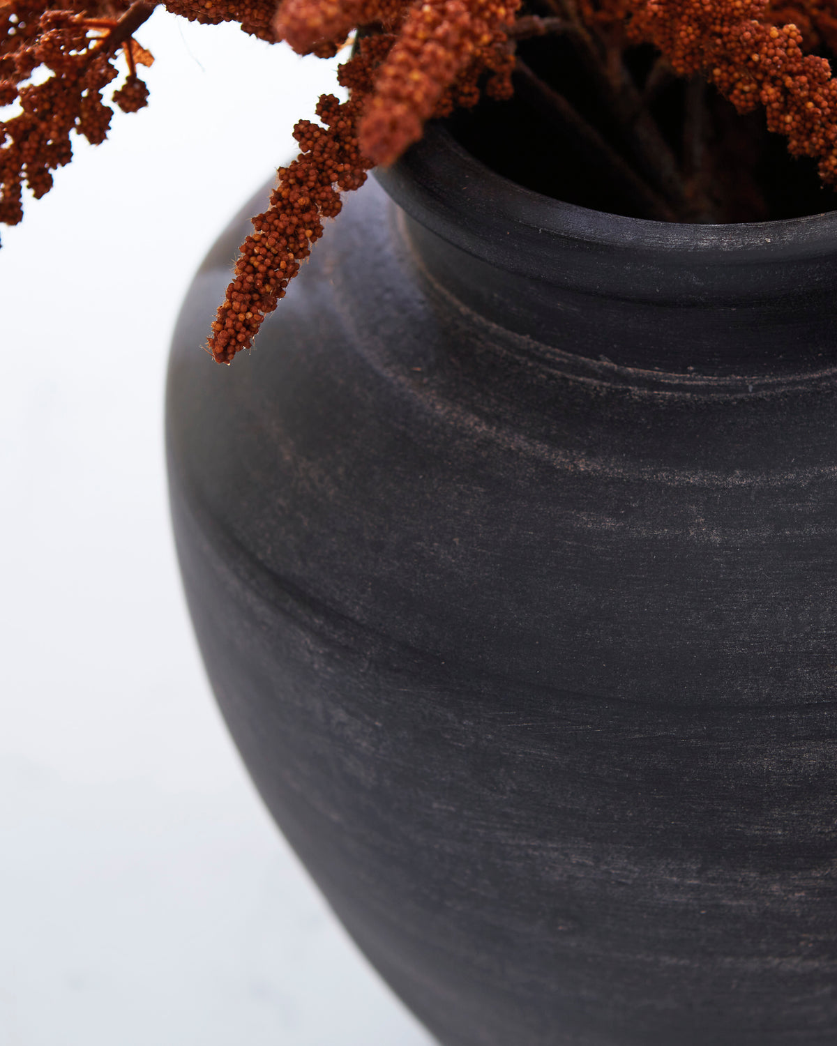 Close-up of Ashley Meadie dark textured vase neck with rust stems