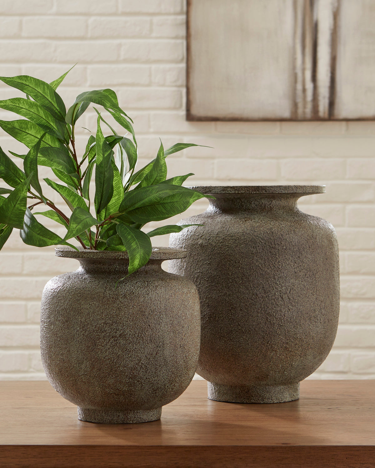 Pair of textured ceramic vases with flared openings and green plant stems, dark gray