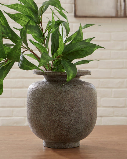 Textured ceramic vase holding artificial green stems, dark gray speckled surface