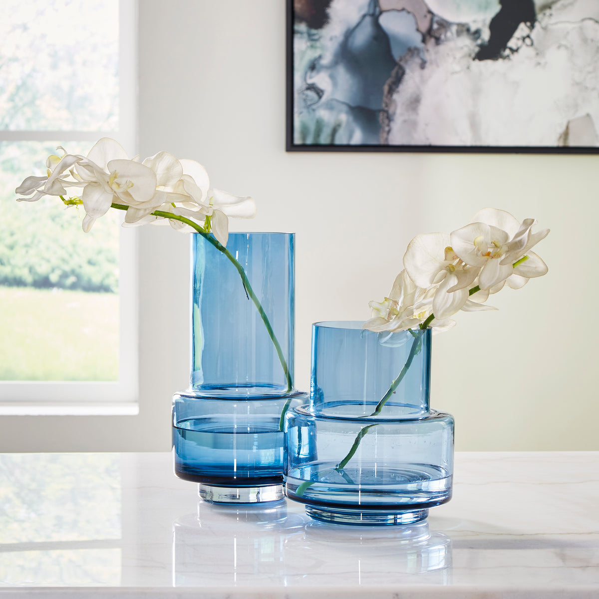 Blue glass vase with white orchids, round base and stacked cylindrical shape