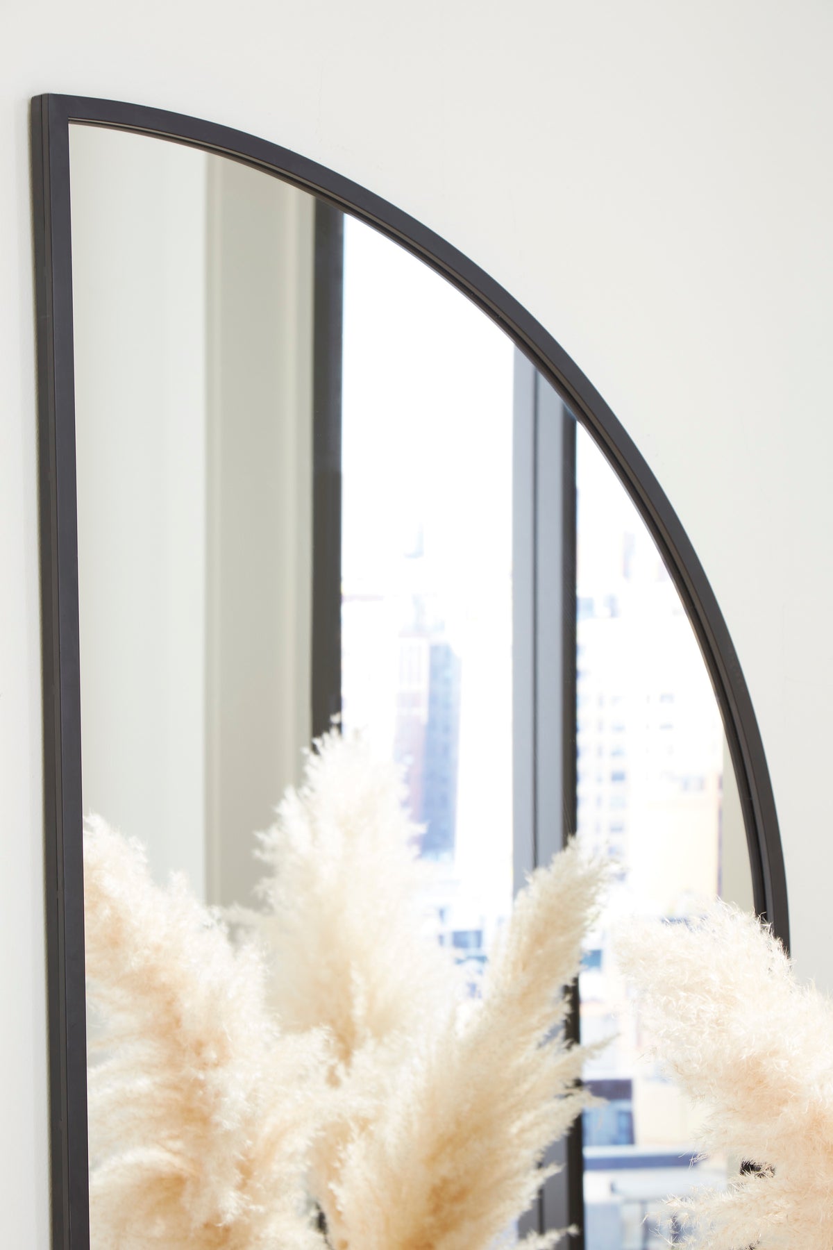 Black-framed arched accent mirror with curved profile and reflective glass