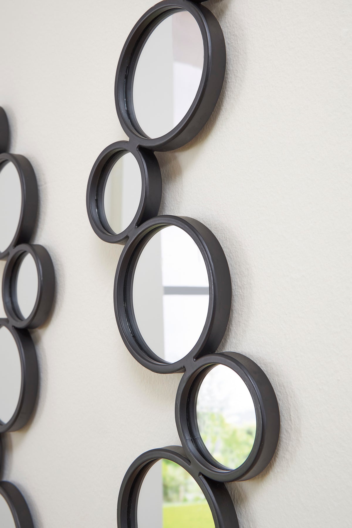 Round accent mirrors set with dark frames and circular mirrored reflections