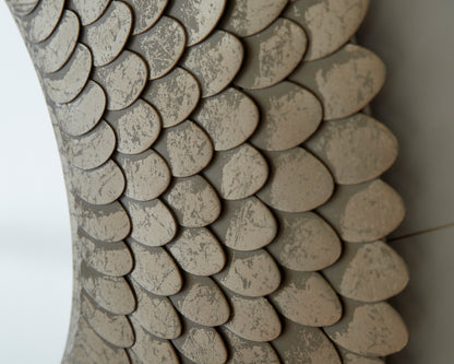 Close-up of shell-textured beige mirror frame with overlapping scales