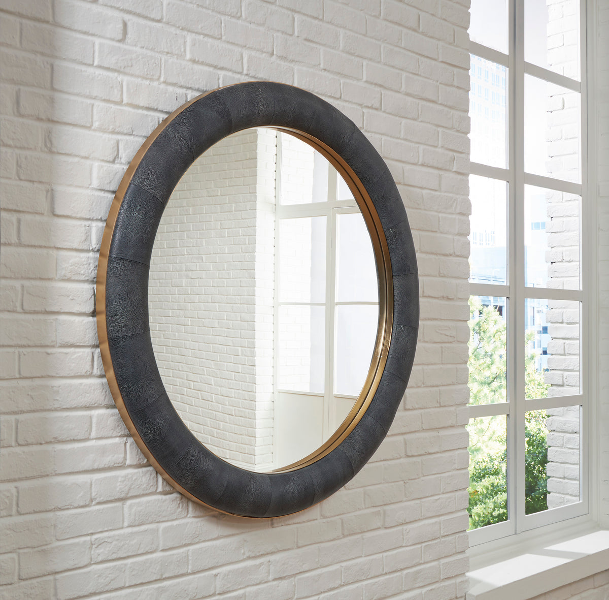 Oval accent mirror with dark textured frame and warm wood-toned inner edge