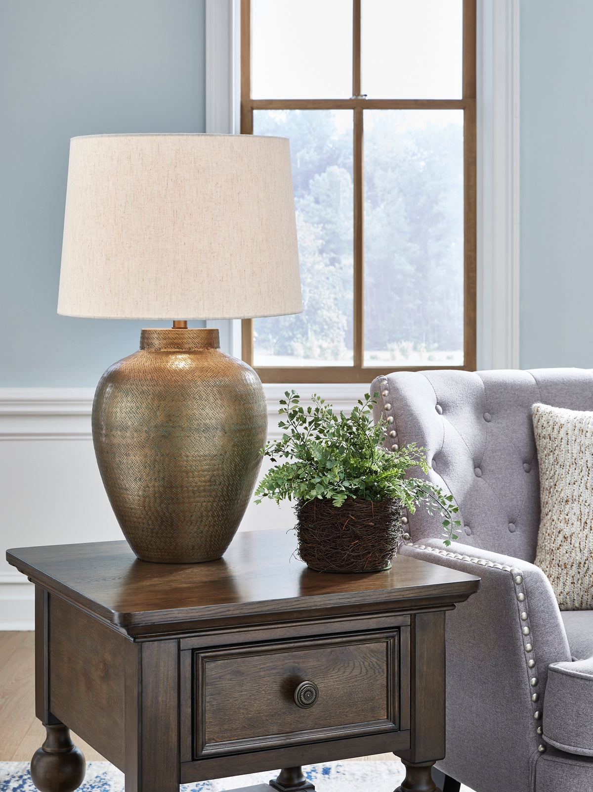 Table lamp with beige fabric drum shade and textured bronze metal base