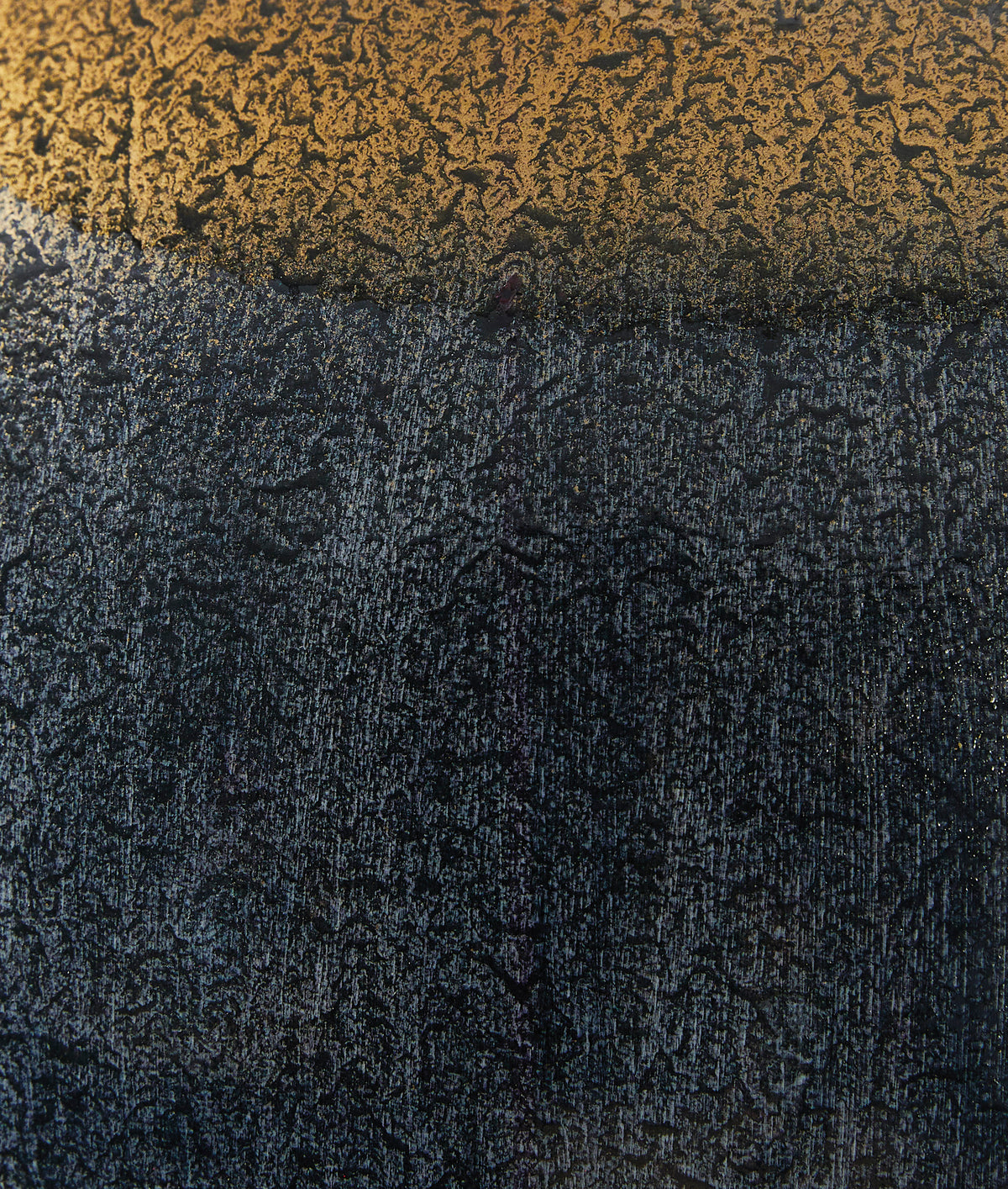 Close-up of lamp base finish: dark textured metal with gold rim