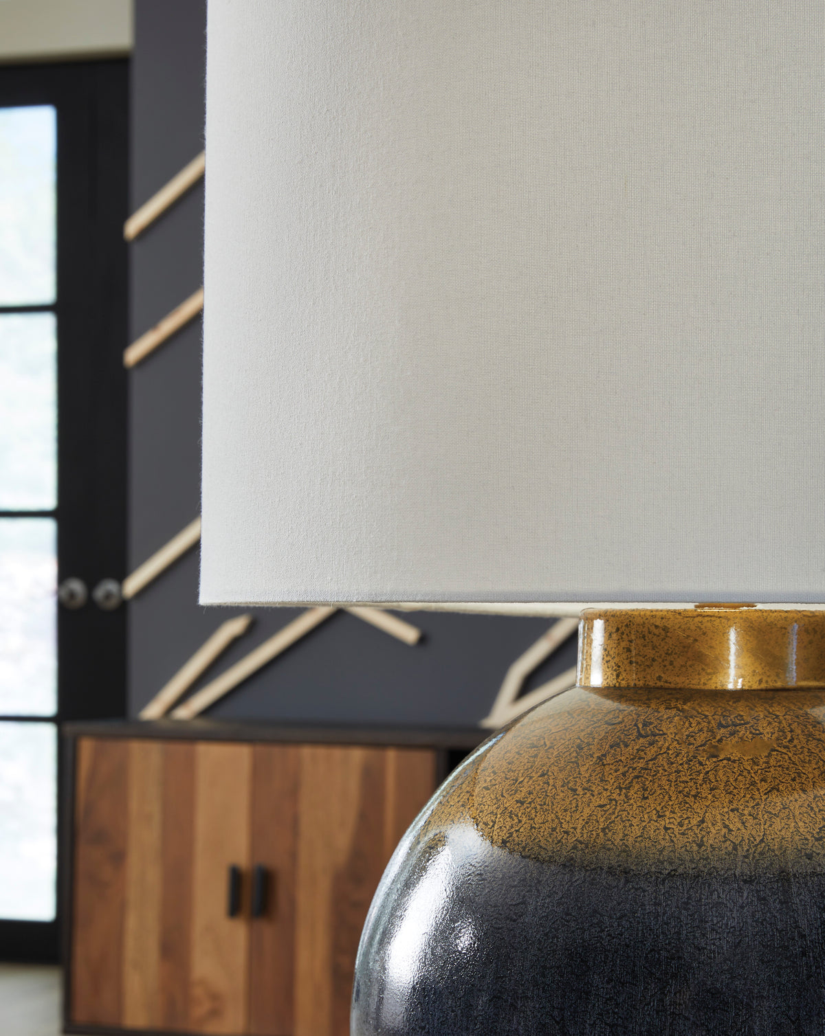 Lamp with white shade over dark textured metal base and gold collar