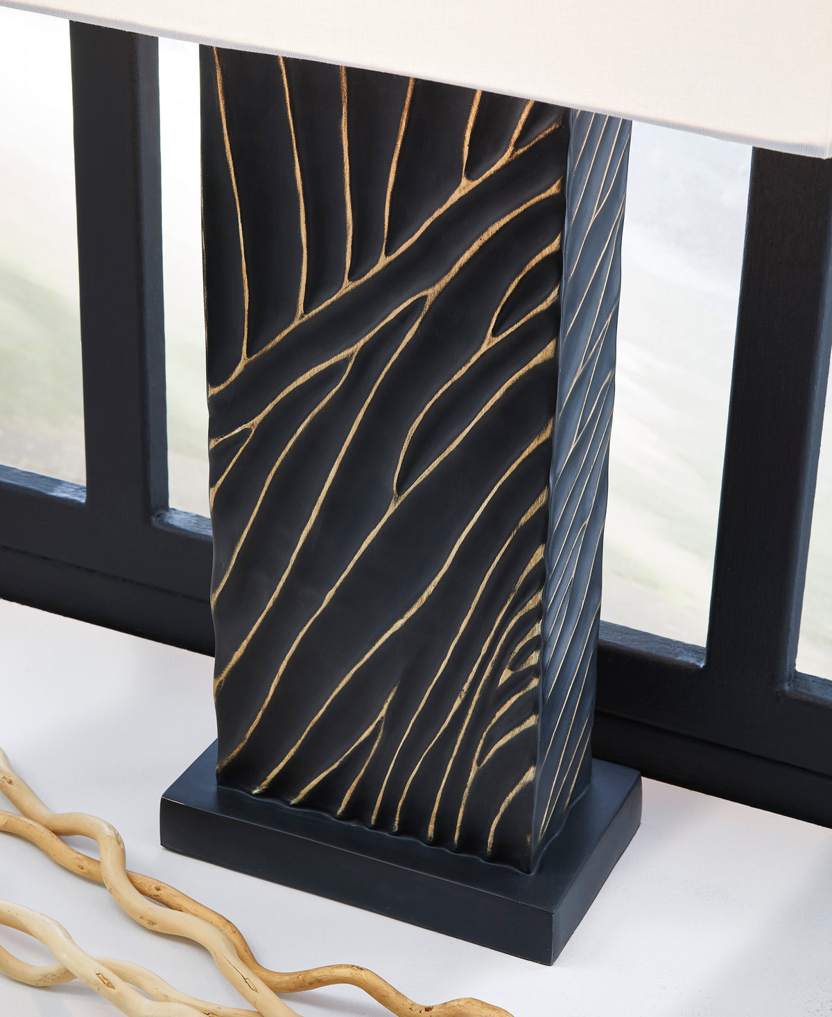 Black table lamp base with gold wavy line pattern and white fabric shade