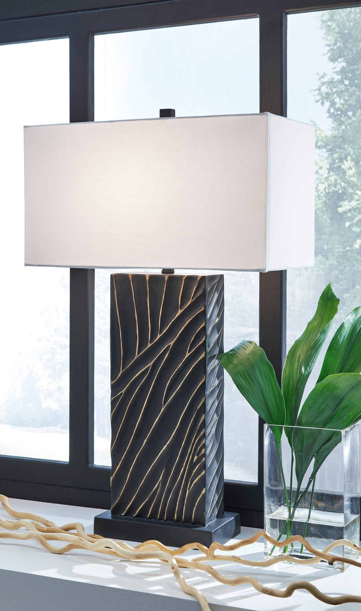 Black table lamp with white fabric shade and gold linear leaf-pattern base