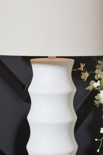 White ribbed ceramic table lamp with beige fabric drum shade, close-up