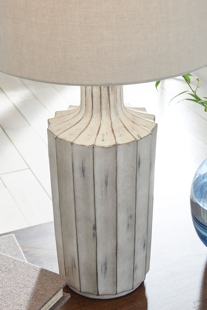 Table lamp close-up: beige drum shade on fluted gray ceramic pedestal base