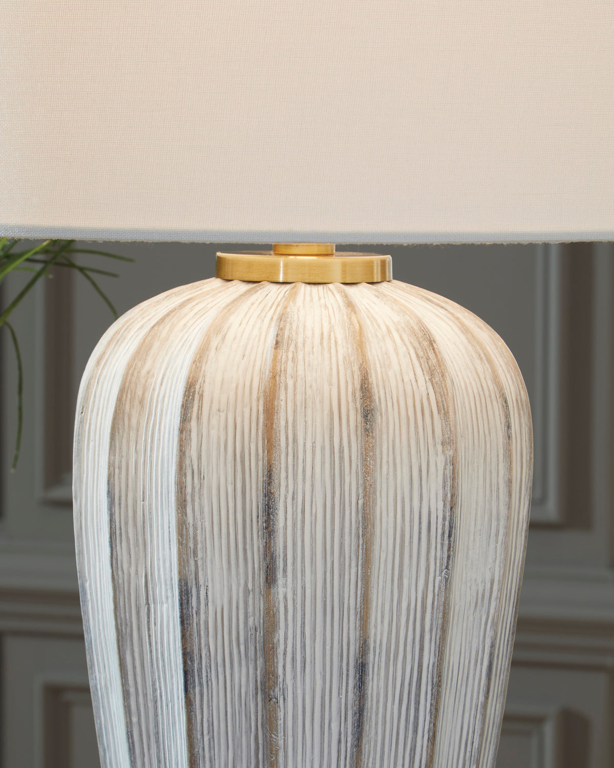 Striped ceramic table lamp base with gold top cap beneath white drum shade