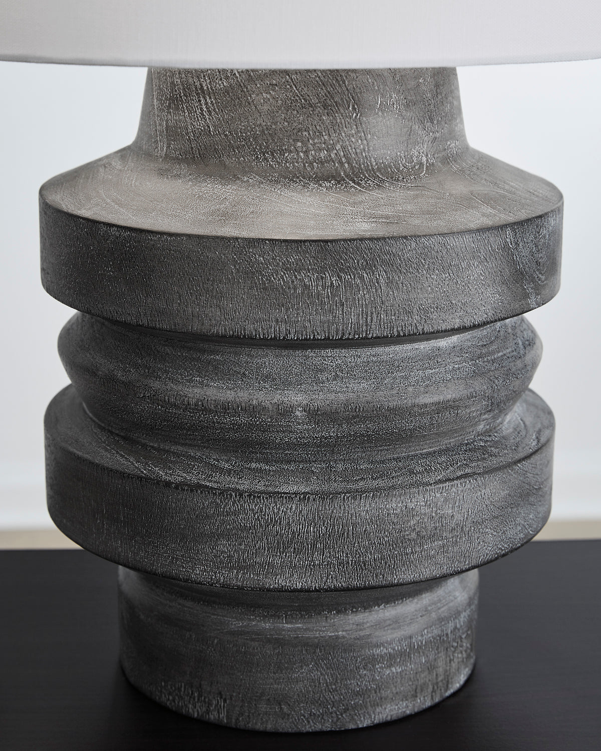 Table lamp base with dark gray stacked ring texture, close-up of top section
