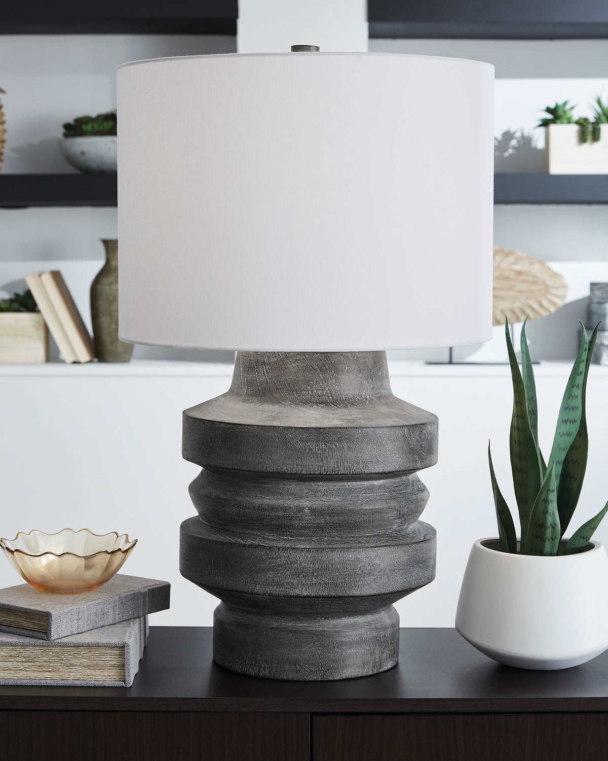 Table lamp with white drum shade and dark gray stacked ring base on tabletop