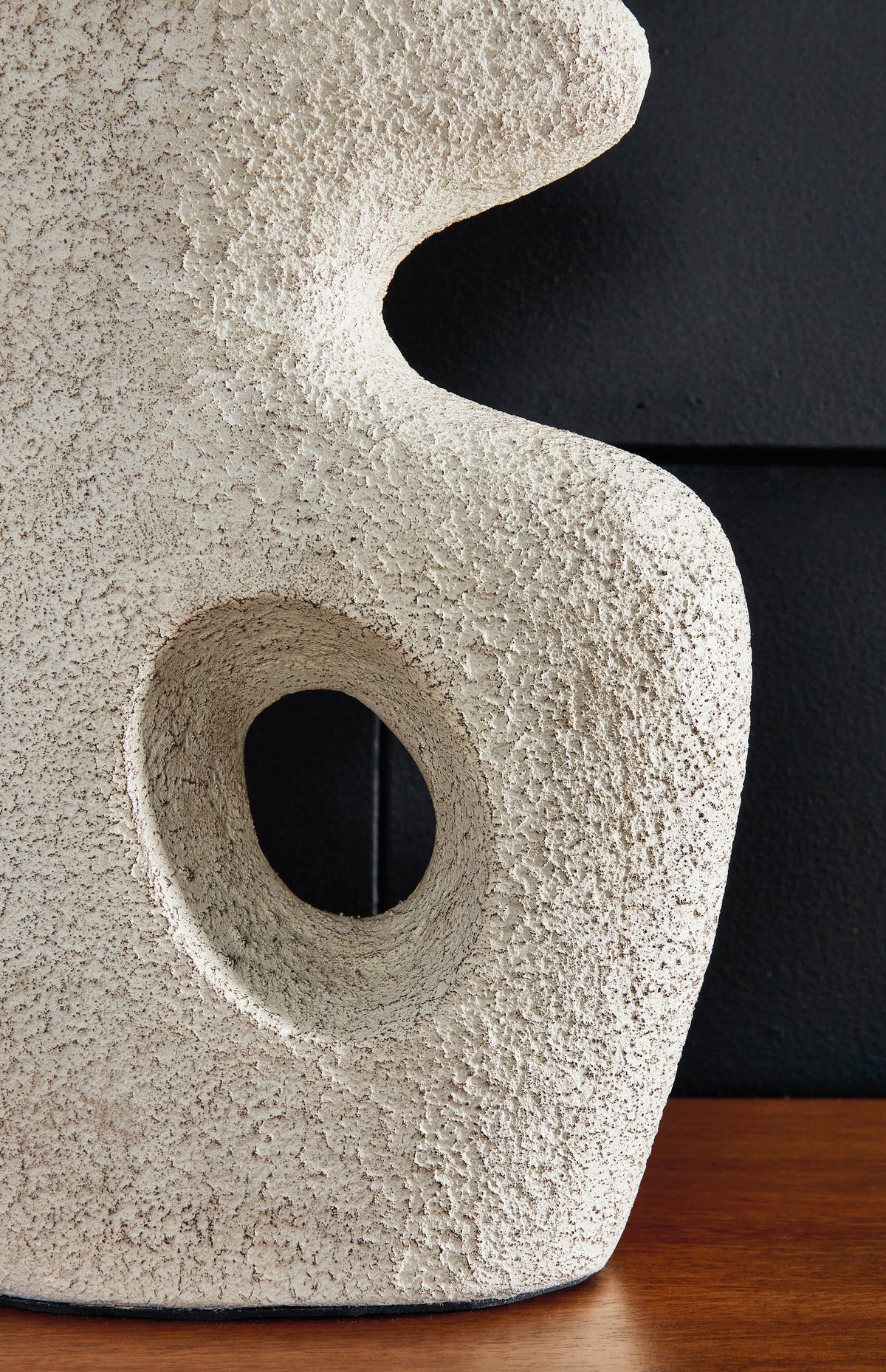 Close-up of textured ceramic table lamp base with oval cutout and curved shape