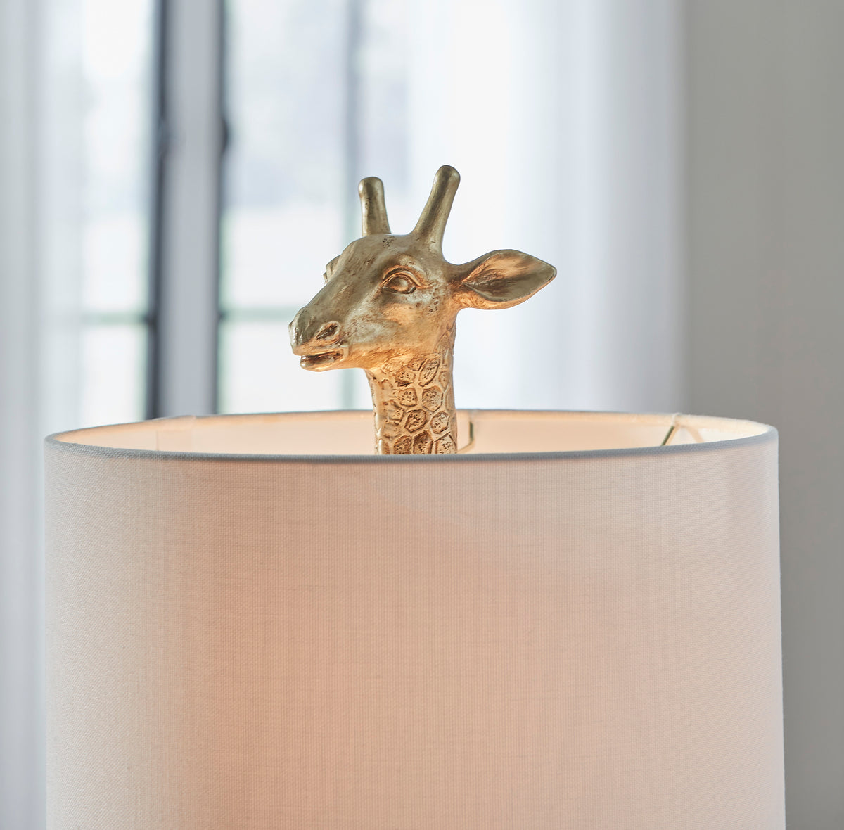 Table lamp close-up: giraffe head emerging from beige drum shade