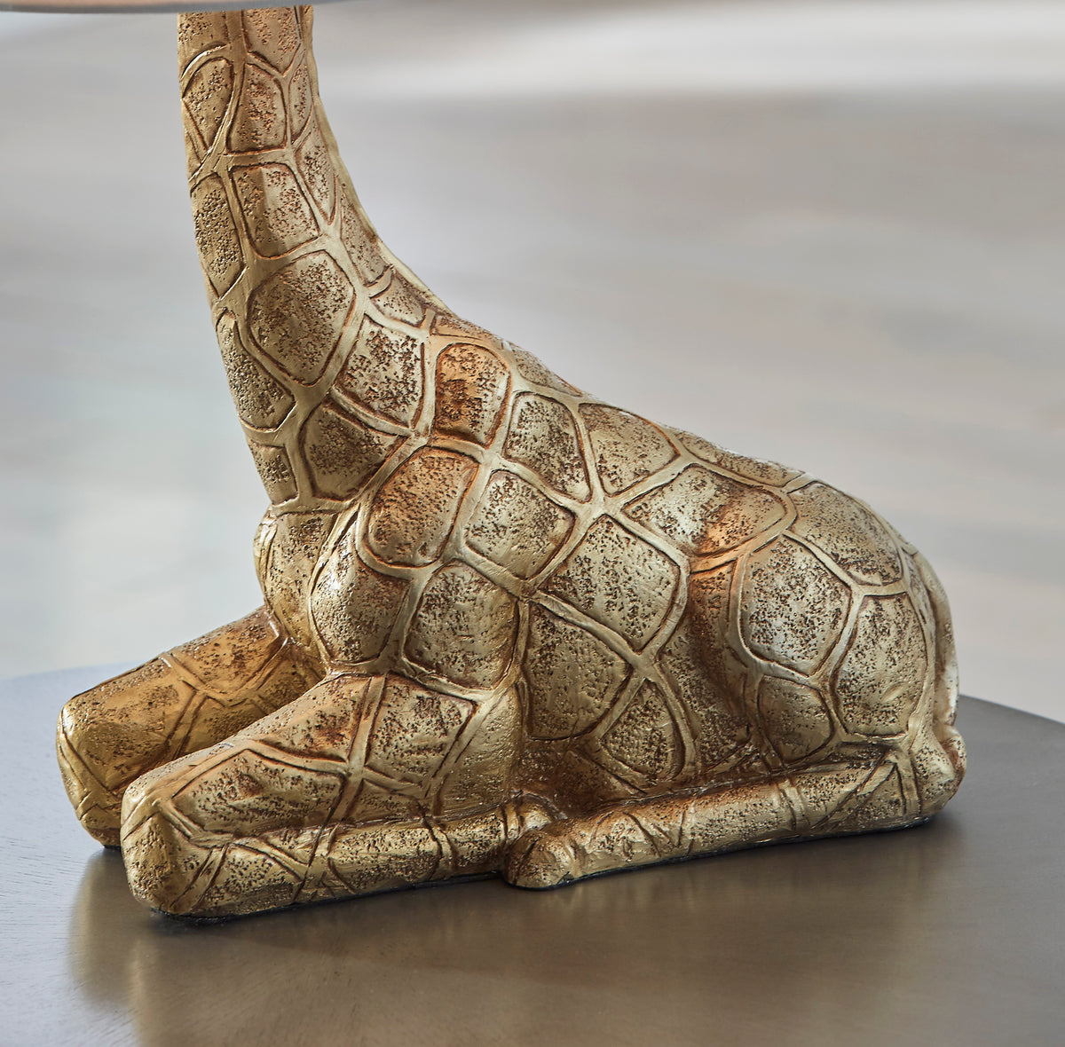 Giraffe base table lamp detail, textured gold-toned body on flat base