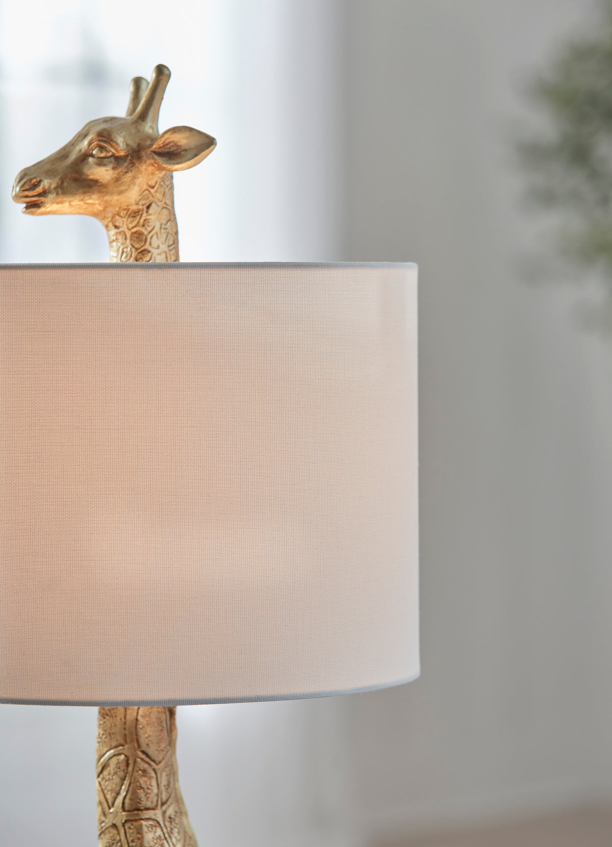 Table lamp side view with giraffe head and beige drum shade
