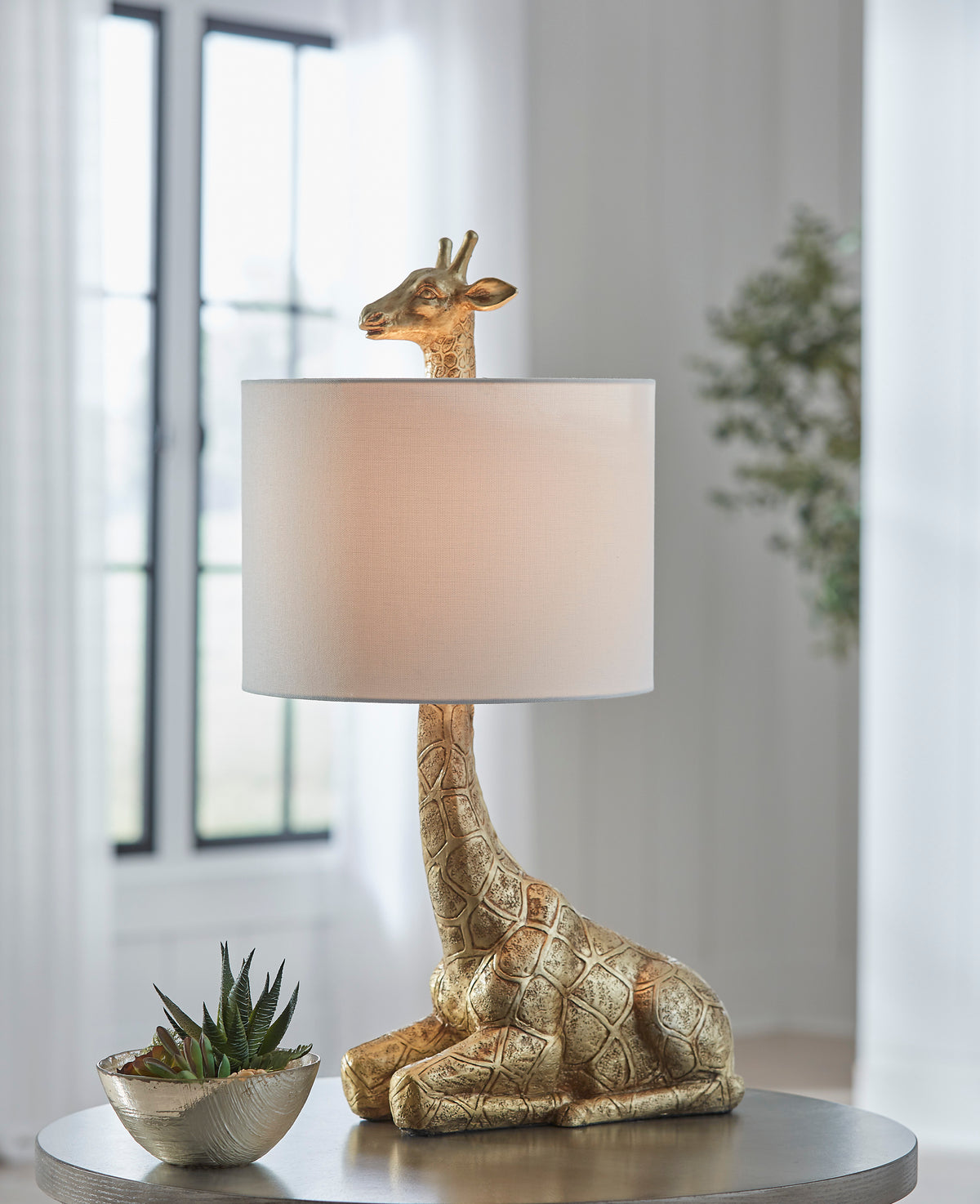Table lamp with giraffe figure base and beige drum shade