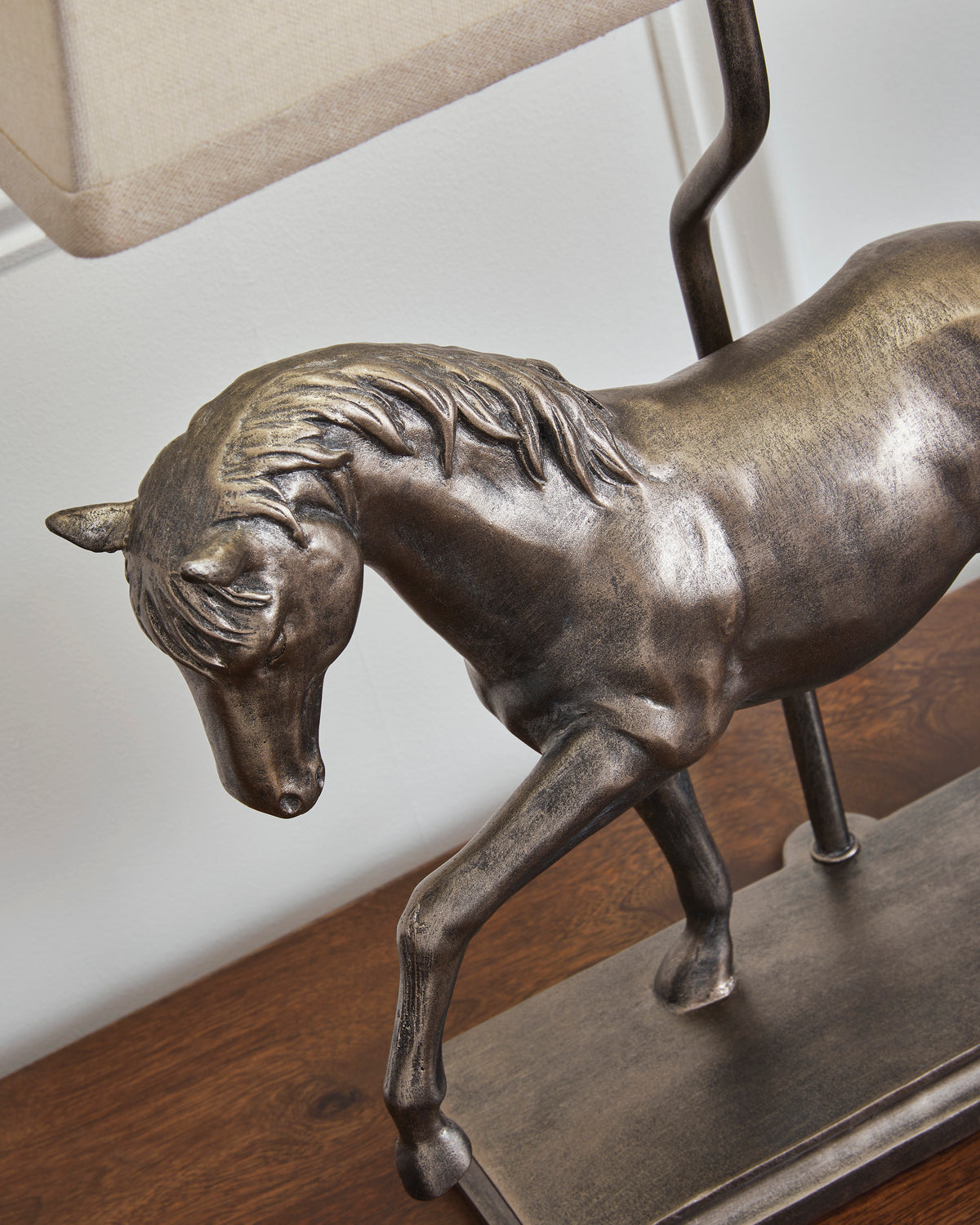 Bronze horse figurine detail on table lamp base with beige shade edge